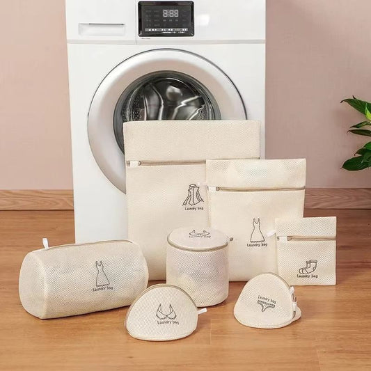 Set of laundry bags in front of a washing machine on a wooden floor.